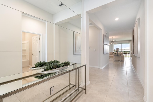 hall featuring light tile patterned floors and a chandelier