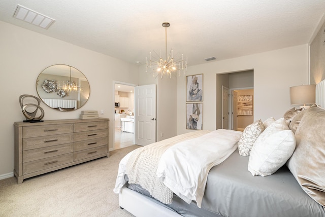 bedroom featuring ensuite bathroom, a chandelier, light carpet, and a textured ceiling