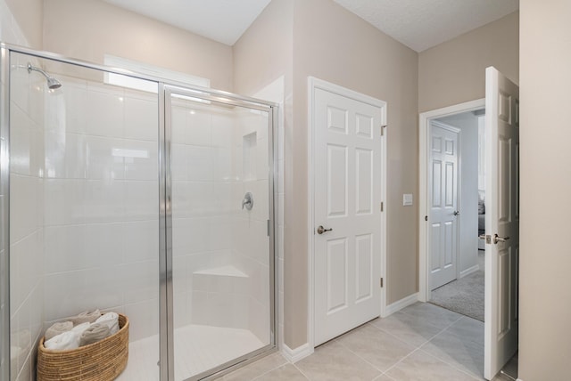 bathroom with an enclosed shower and tile patterned floors