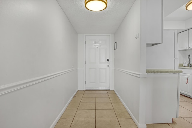 entryway with light tile patterned floors and a textured ceiling