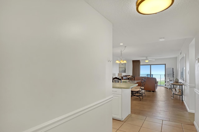 hall featuring a textured ceiling, a notable chandelier, and light tile patterned flooring