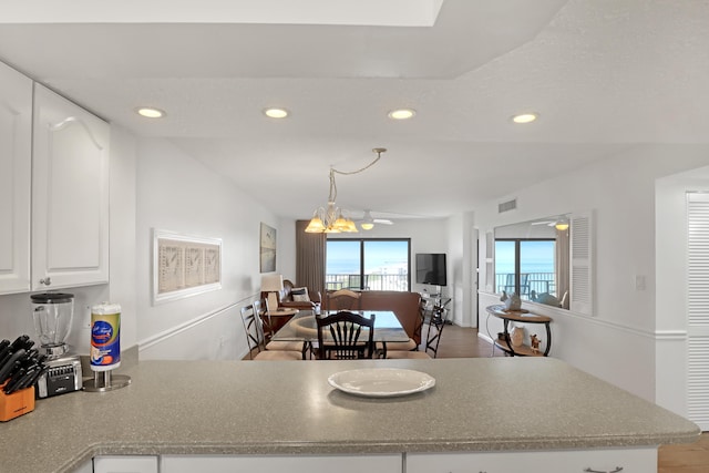 kitchen featuring white cabinetry and ceiling fan with notable chandelier