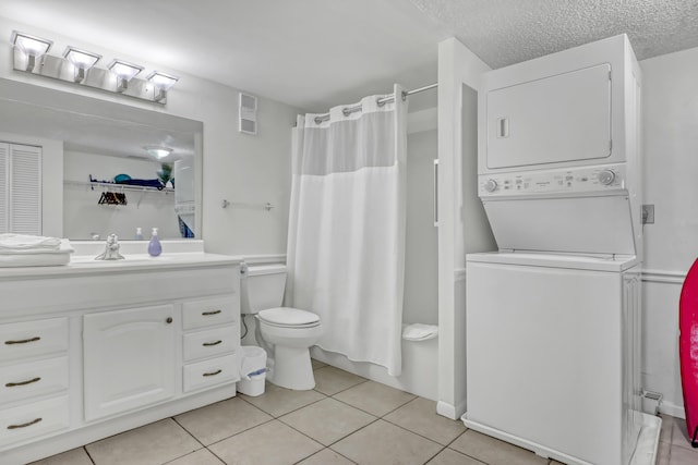 bathroom featuring vanity, tile patterned flooring, toilet, a textured ceiling, and stacked washer / drying machine