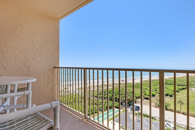 balcony with a water view and a view of the beach