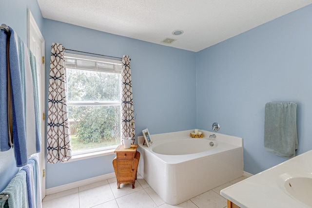 bathroom with vanity, a textured ceiling, a tub to relax in, and tile patterned floors