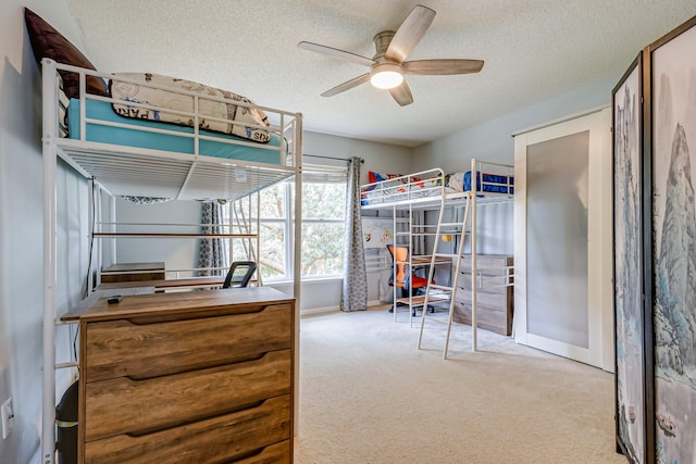 bedroom featuring a textured ceiling, light colored carpet, and ceiling fan