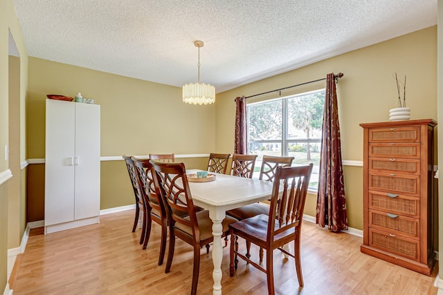 dining room featuring a textured ceiling, an inviting chandelier, and light hardwood / wood-style flooring