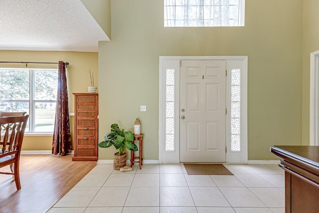 foyer featuring light hardwood / wood-style flooring, a high ceiling, and a textured ceiling