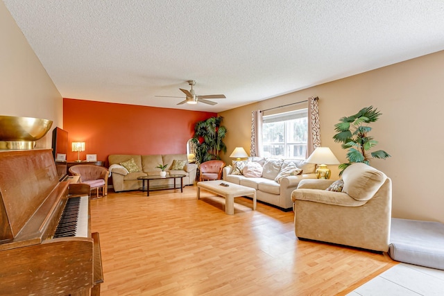 living room featuring hardwood / wood-style flooring, ceiling fan, and a textured ceiling