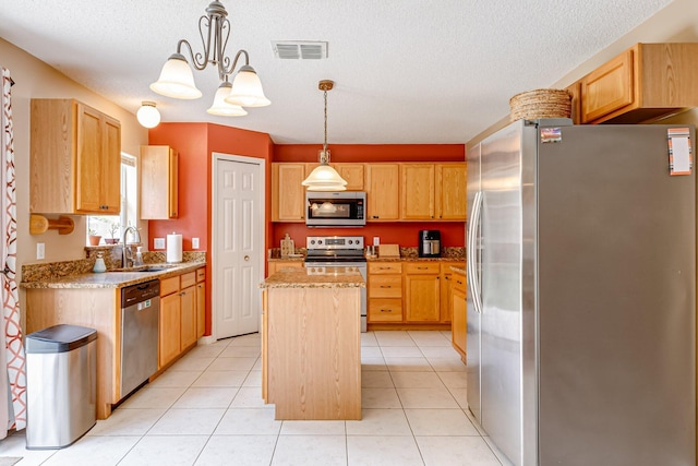 kitchen featuring appliances with stainless steel finishes, light tile patterned floors, decorative light fixtures, a chandelier, and a center island