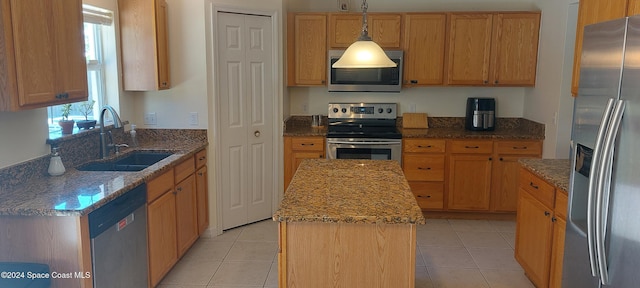 kitchen featuring a center island, sink, light tile patterned floors, appliances with stainless steel finishes, and decorative light fixtures