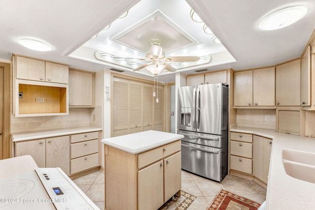 kitchen with a center island, stainless steel refrigerator with ice dispenser, a tray ceiling, and ceiling fan