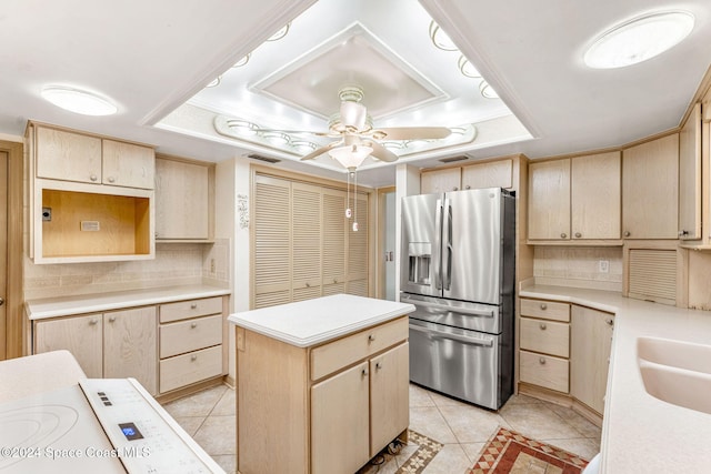 kitchen featuring light tile patterned flooring, light brown cabinets, stainless steel refrigerator with ice dispenser, a tray ceiling, and backsplash