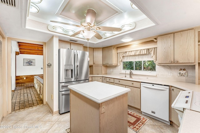 kitchen with light brown cabinetry, a kitchen island, a raised ceiling, white dishwasher, and stainless steel fridge