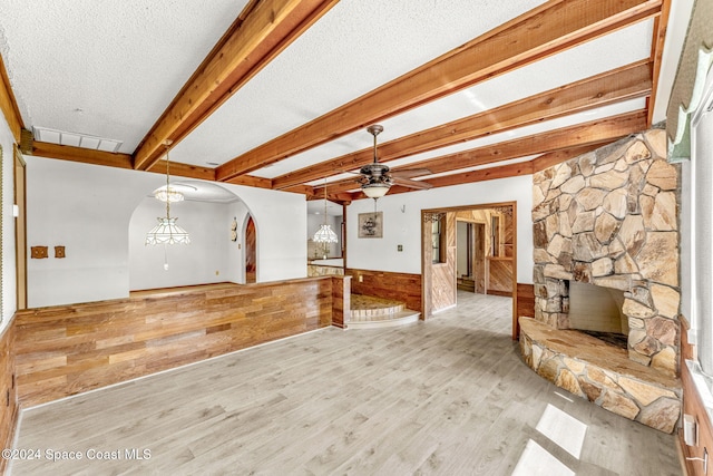 unfurnished living room featuring wooden walls, ceiling fan, a wainscoted wall, wood finished floors, and visible vents
