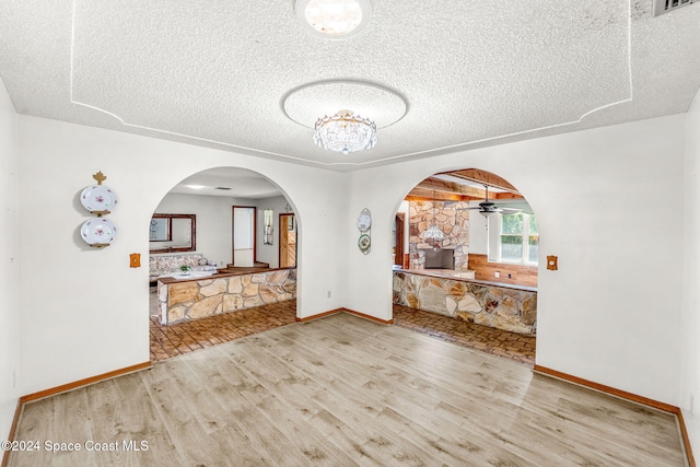 unfurnished dining area featuring a textured ceiling, light hardwood / wood-style flooring, and ceiling fan with notable chandelier