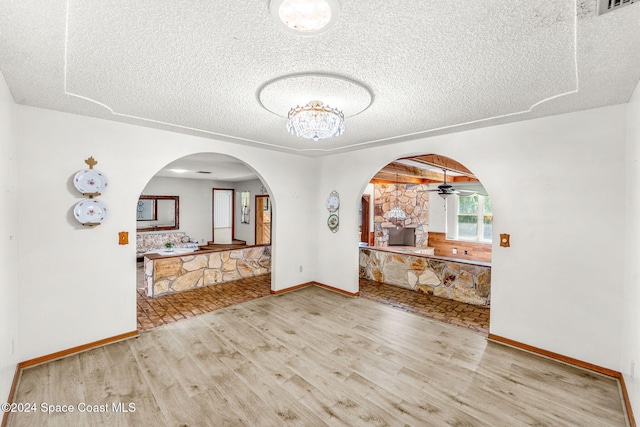 interior space with wood finished floors, baseboards, a textured ceiling, arched walkways, and ceiling fan with notable chandelier