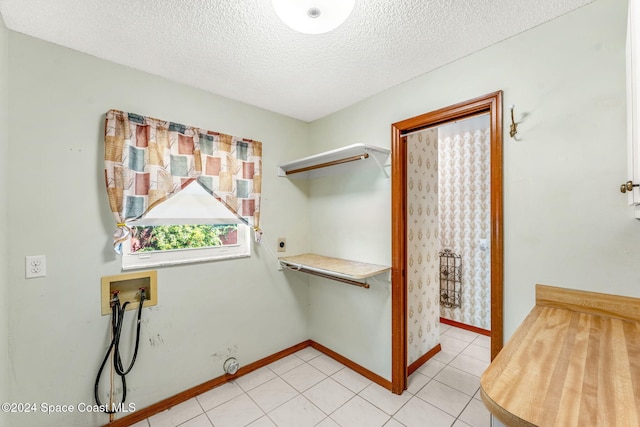 clothes washing area with laundry area, baseboards, hookup for a washing machine, a textured ceiling, and electric dryer hookup