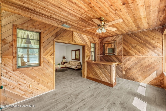 additional living space with ceiling fan, wooden ceiling, wooden walls, and hardwood / wood-style floors