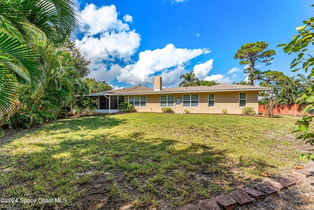 back of house featuring a sunroom and a lawn