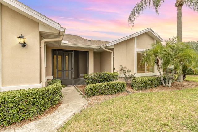 exterior entry at dusk with a yard and french doors