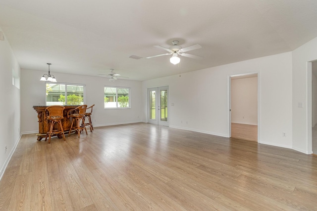 living room with ceiling fan with notable chandelier and light hardwood / wood-style flooring