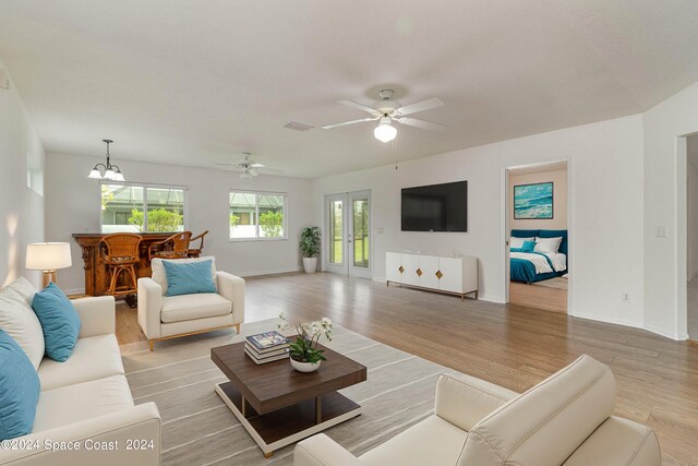 living room featuring ceiling fan with notable chandelier and light hardwood / wood-style floors