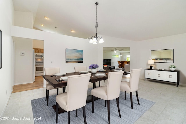 tiled dining area featuring vaulted ceiling and ceiling fan with notable chandelier