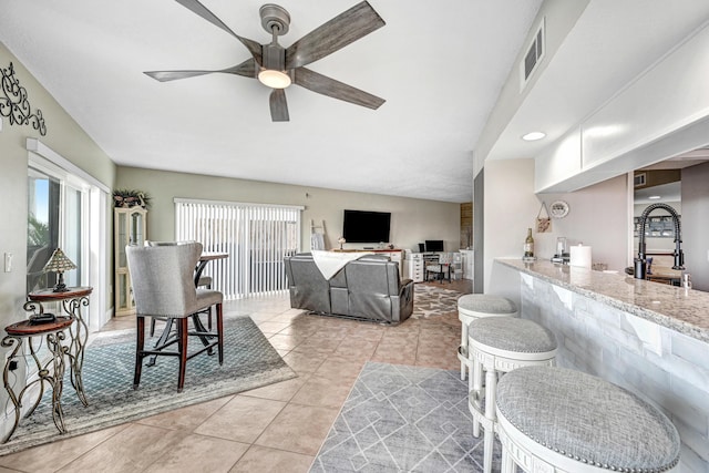 living room featuring light tile patterned floors, sink, and ceiling fan