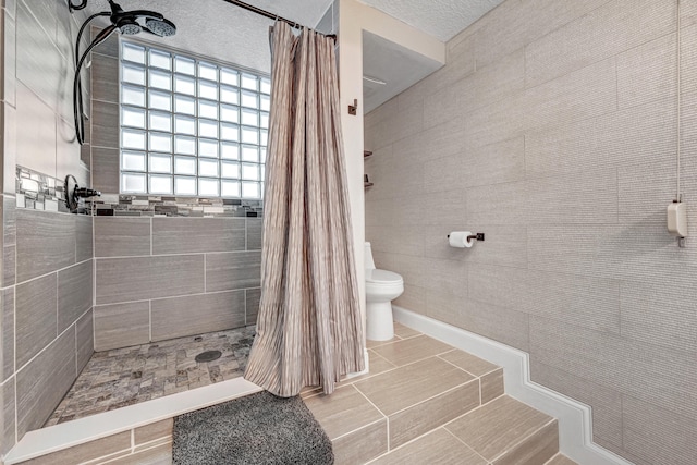 bathroom featuring toilet, tile patterned flooring, a shower with shower curtain, and tile walls