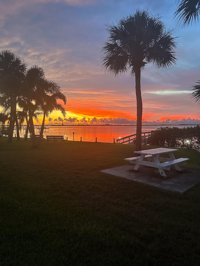 yard at dusk with a water view and a patio area