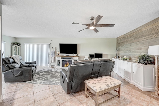 living room featuring ceiling fan, light tile patterned floors, a textured ceiling, and wooden walls