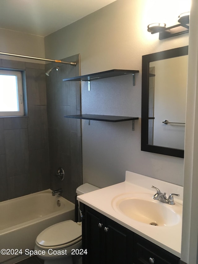 full bathroom with tiled shower / bath, vanity, and toilet