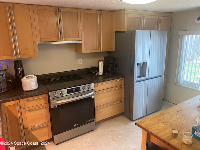 kitchen with appliances with stainless steel finishes, a textured ceiling, and light tile patterned floors