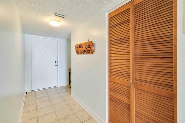 corridor with a textured ceiling and light tile patterned flooring