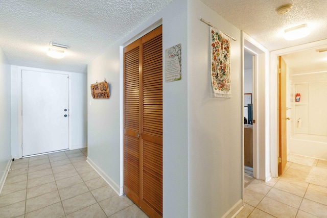 hall with light tile patterned floors and a textured ceiling
