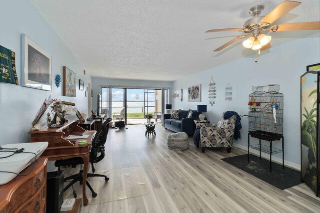 home office with ceiling fan, light hardwood / wood-style floors, and a textured ceiling