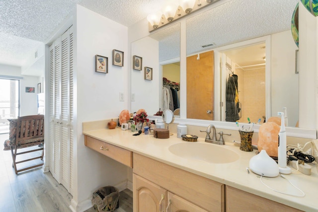 bathroom with hardwood / wood-style flooring, vanity, and a textured ceiling