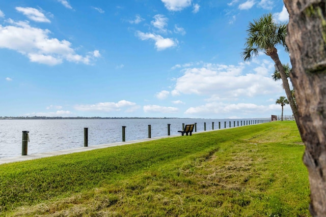 dock area with a lawn and a water view