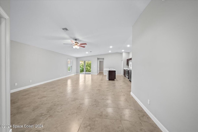 unfurnished living room with ceiling fan, vaulted ceiling, and light tile patterned floors