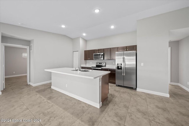 kitchen with lofted ceiling, sink, a kitchen island with sink, dark brown cabinetry, and stainless steel appliances