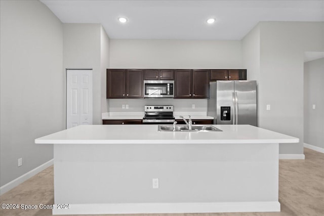 kitchen with stainless steel appliances, sink, a kitchen island with sink, and dark brown cabinets