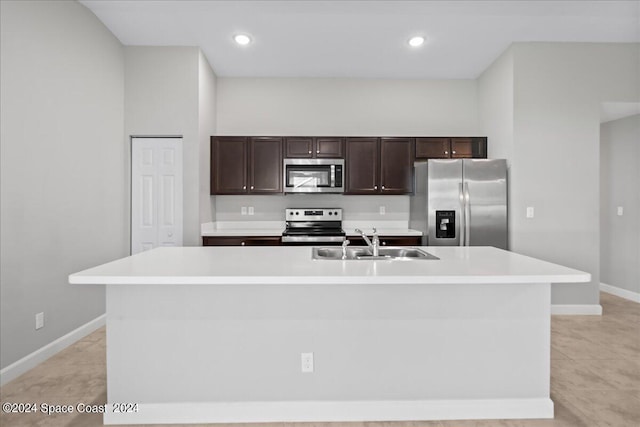 kitchen featuring dark brown cabinetry, sink, stainless steel appliances, and a center island with sink