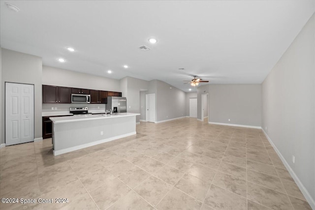 kitchen featuring lofted ceiling, ceiling fan, dark brown cabinets, stainless steel appliances, and an island with sink