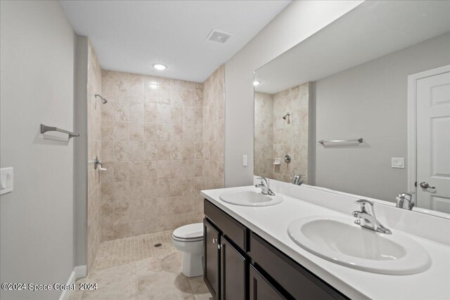 bathroom featuring toilet, a tile shower, tile patterned floors, and vanity