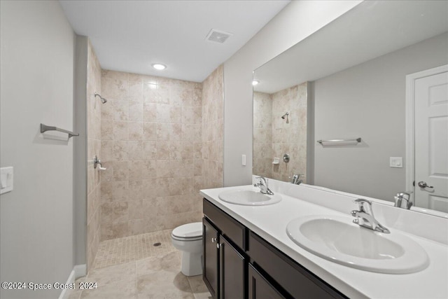 bathroom featuring tile patterned flooring, vanity, tiled shower, and toilet