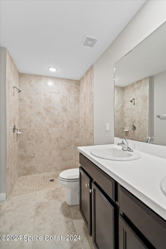 bathroom featuring a tile shower, vanity, and toilet