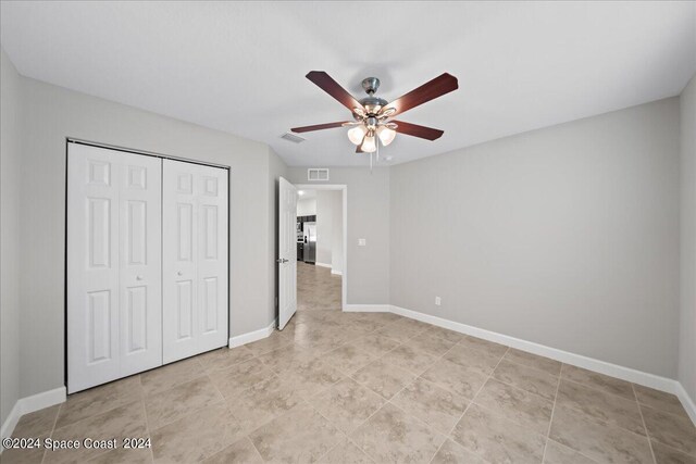 unfurnished bedroom featuring ceiling fan, stainless steel fridge with ice dispenser, and a closet