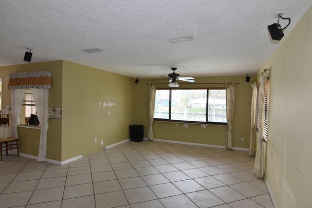 spare room featuring ceiling fan, light tile patterned floors, and a textured ceiling