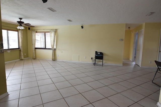 spare room with ceiling fan, light tile patterned flooring, and a textured ceiling